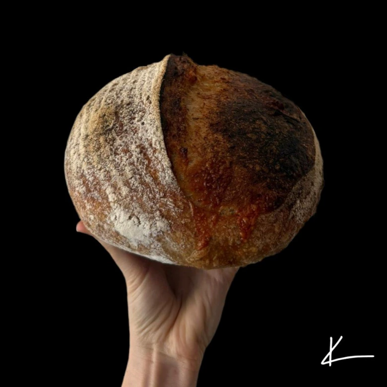 Rukou držený domácí kváskový chléb s křupavou korunkou.