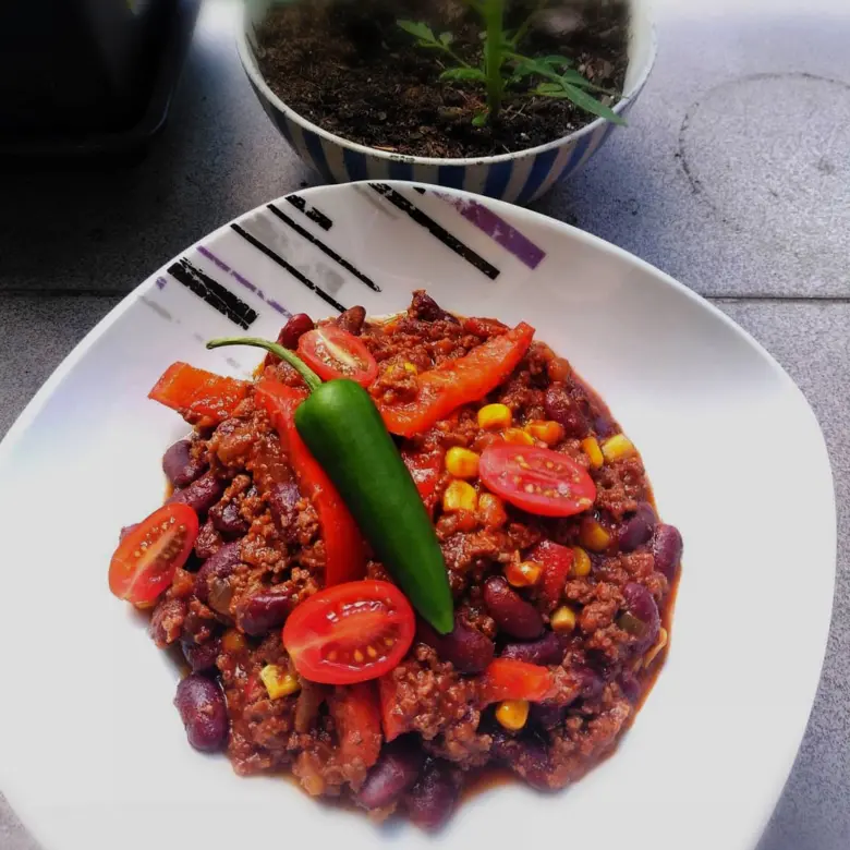 Položka chilli s fazolemi na bílé talíři.