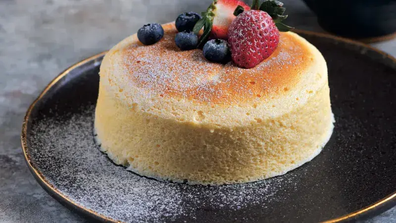 Japonský cheesecake s ovocem na tmavém talíři.