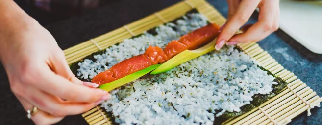 Hands making sushi roll