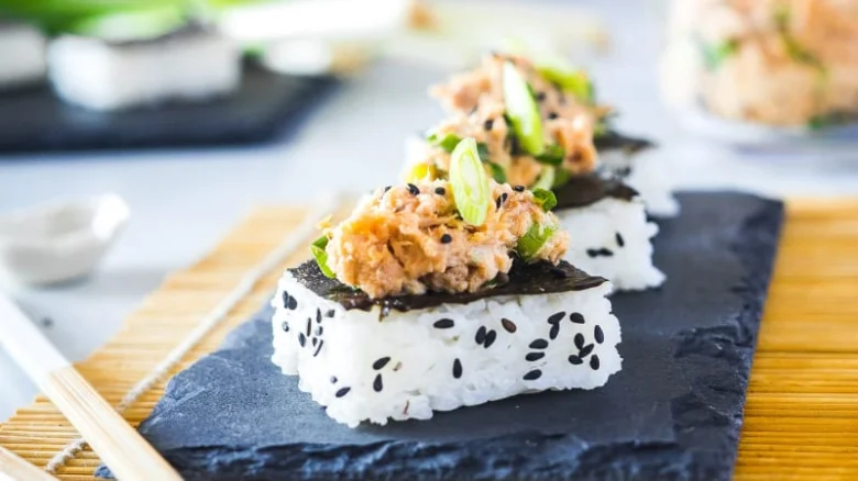 Tři kusy tunového sushí na černé desce.