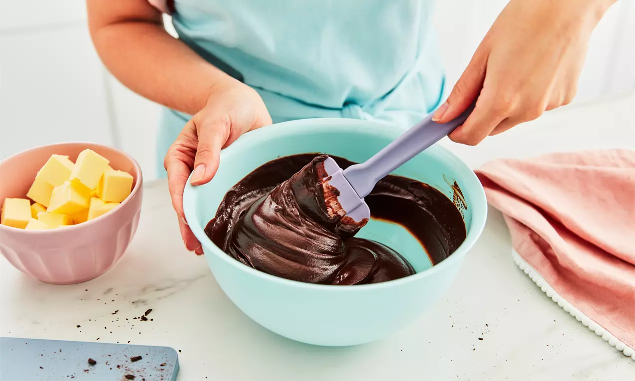 Míchání čokoládové ganache v míse s lžící.