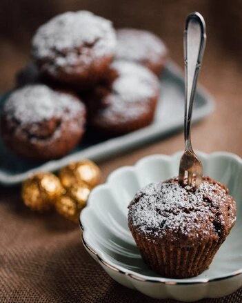 Hrnkové muffiny z čokolády posypané cukrem na talíři.
