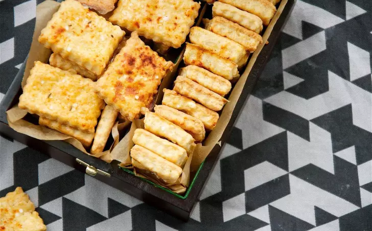 Dřevěná krabička s čtvercovými slanoumi sušenkami ze sýra.