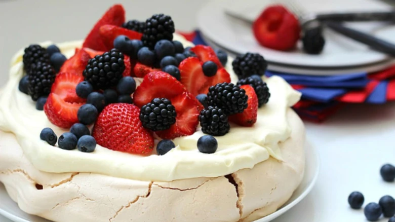 Celý dezert Pavlova s čerstvými jahodami a malinami.