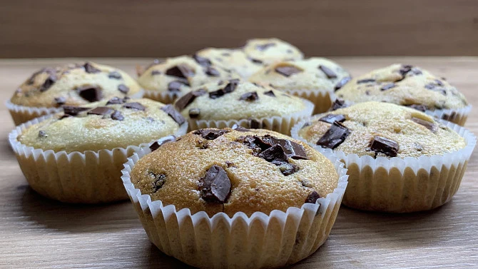 Domácí muffiny s čokoládovými kousky na dřevěném povrchu.