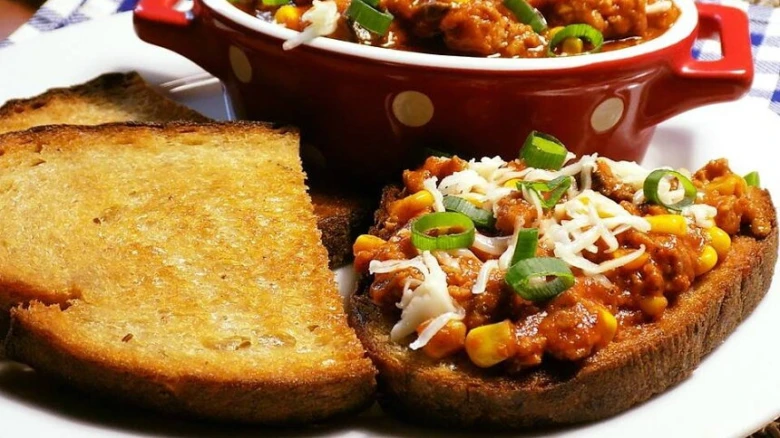 Topinky s chilli, sýrem a cibulkou na bílém talíři.