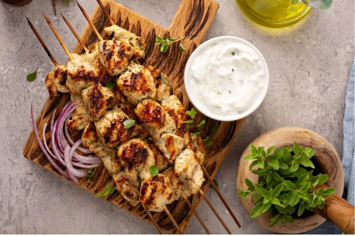 Pečené kuřecí souvlak na špejlech s dipem z jogurtu a čerstvou bazalkou.
