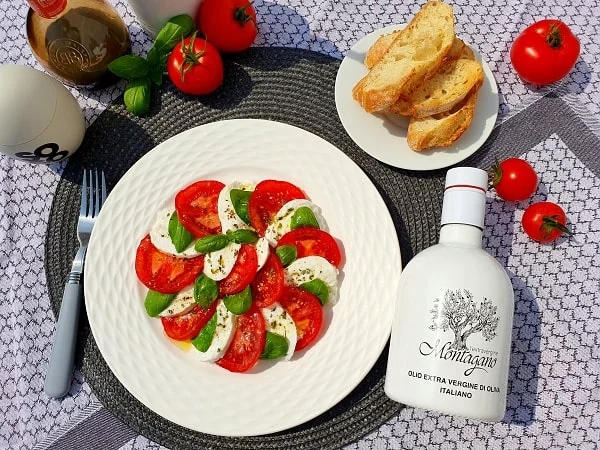Připravený caprese salát s rajčaty, mozzarellou a olivovým olejem.