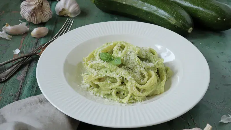 Pasta s cuketovou omáčkou posypaná syrem a bazalkou.