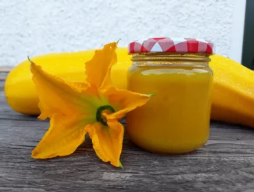 Sklenice cuketové omáčky s květem uzelky na dřevě.
