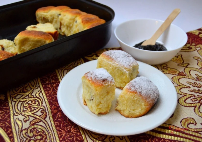Zlaté buchty s povidly na talíři vedle misky plněné.