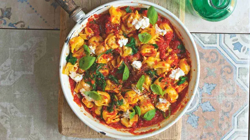 Tortellini s rajčatovou omáčkou, bazalkou a sýrem v pánvi.
