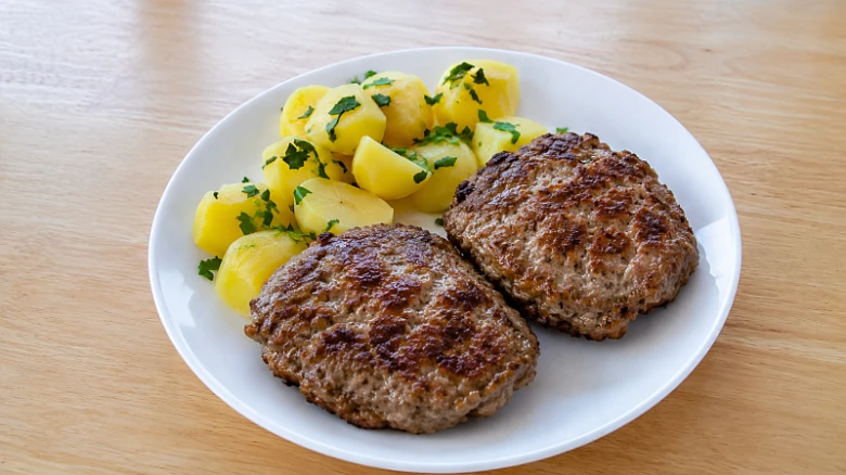 Dva smažené biftečky z mletého masa s vařenými bramborami.