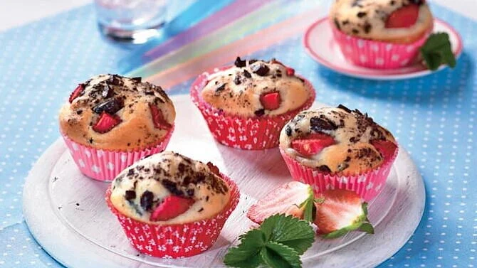 Jahodové muffiny s čokoládovými kousky na bílém talíři.