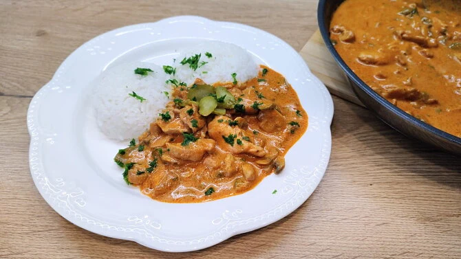 Hot kuřecí stroganov s rýží na bílém talíři.