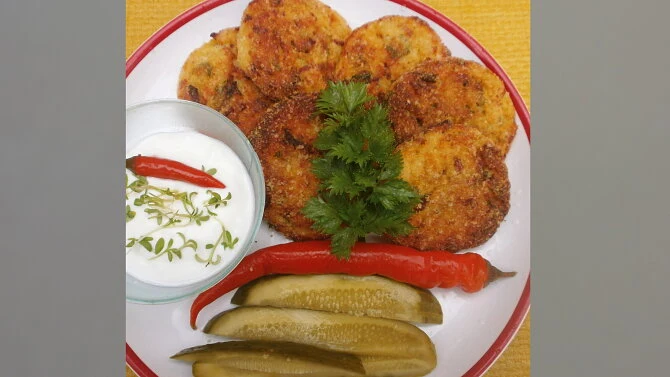 Použité krokety s omáčkou, okurkami a paprikami na talíři.