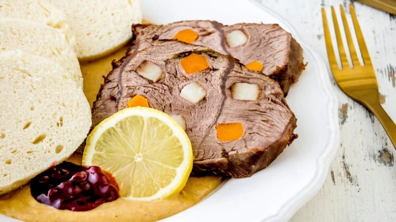 Uzené maso s chlebem a citronovou kůrou na talíři.
