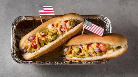 Dva americké hot dogy s vlajkami USA v plechovém podnosu.