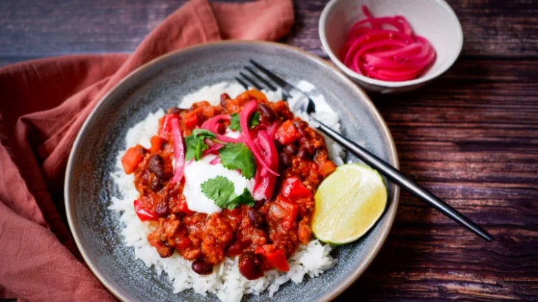 Chilli con carne s podáván na rýži se zakysanou smetanou.