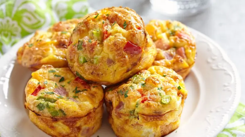 Zlatohnědé vejcové muffiny s uzeninou a zeleninou na talíři.