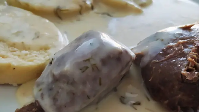 Kus masa v koprové omáčce s chlebem na talíři.