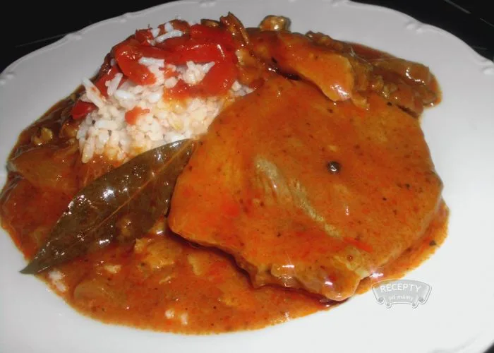 Pork chop in goulash sauce on bed of rice.