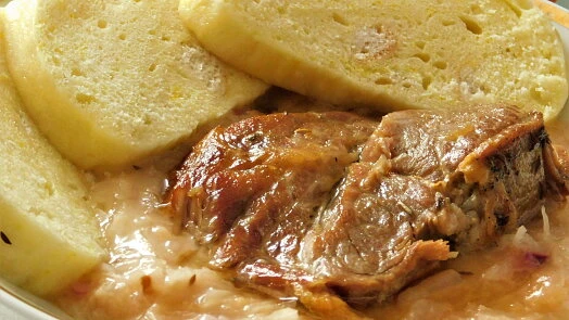 Přesnídané vepřo s knedlíkem a zelím na talíři.