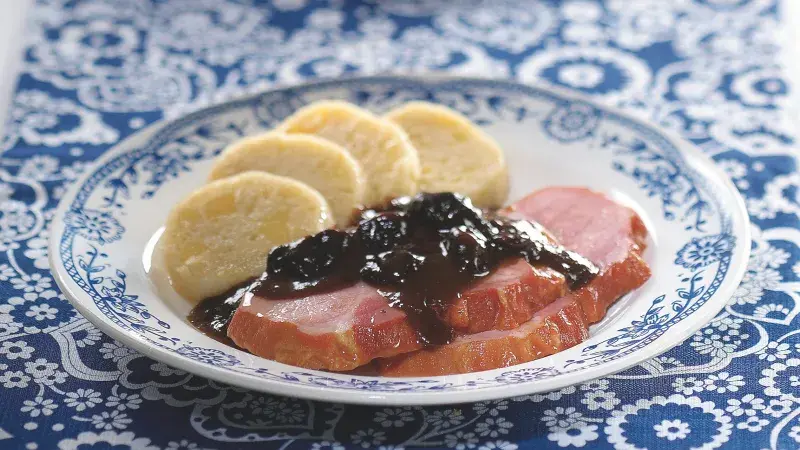 Uzené maso s omáčkou z bobulí a bramborami na talíři.