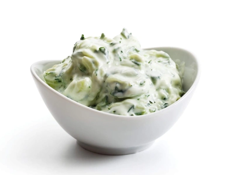 Bílková omáčka tzatziki s bylinkami v bílé misce.