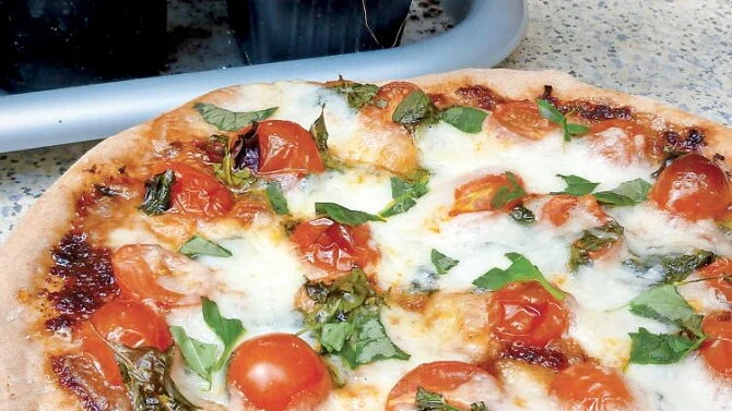 Domácí pizzy Margherita s rajčaty a bazalkou.