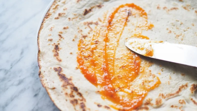Nůž rozšiřuje ovocný džem na palačince.