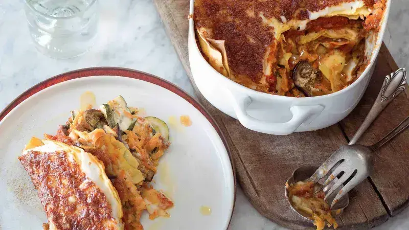 Zeleninové lasagne s baklažánem a cuketou na talíři vedle pekáče.