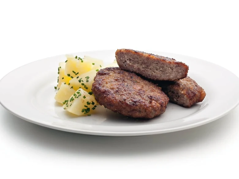 Pár grilovaných karbanátků z masa s bramborami a petrželkou.