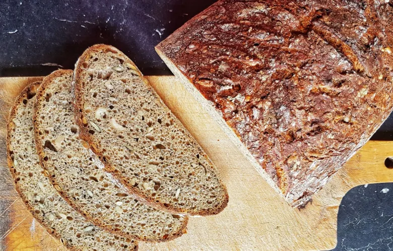 Kousek tmavého chleba z droždí s viditelnou strukturovanou kůrou.