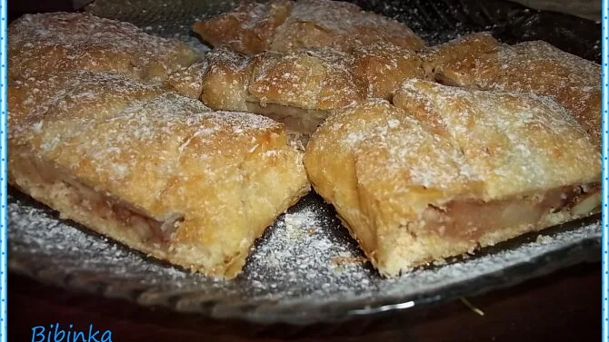 Zlatohnědé štrúdlíky posypané moučkovým cukrem na talíři.