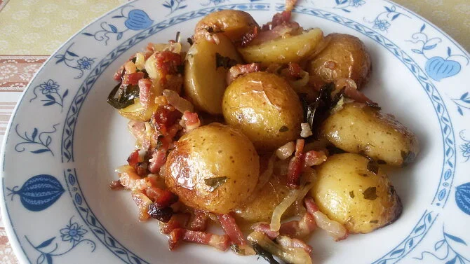 Pekně upékané farmářské brambory se slaninou na talíři.