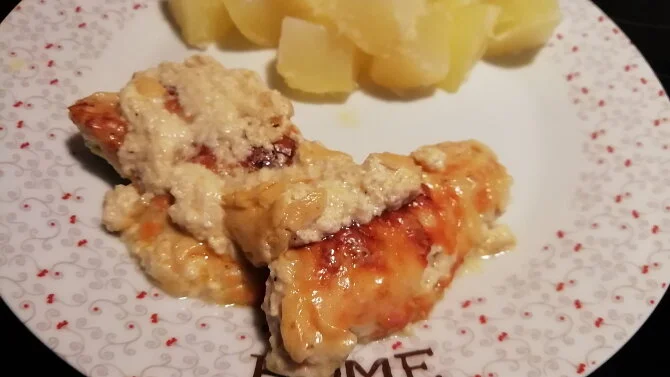 Zapečené kuřecí maso se sýrem a smetanou na talíři.
