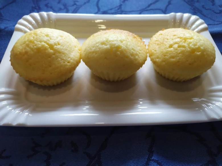 Tři zapečené hrníčkové muffiny na bílém podnose.