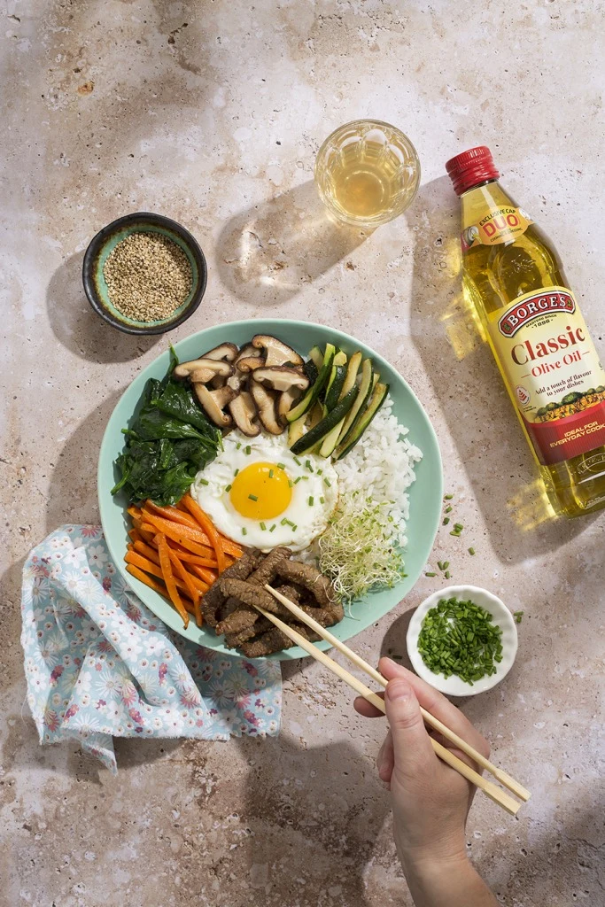 Bibimbap s rýží, vejcem, zeleninou a masem na talíři.