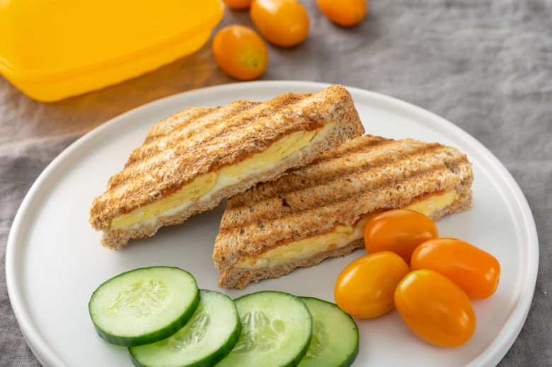 Grilovaný toasty s vejcem na bílém talíři se zeleninou.