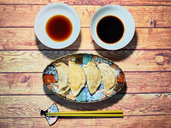 Japonské gyoza knedlíčky s omáčkami na dřevěném stole.