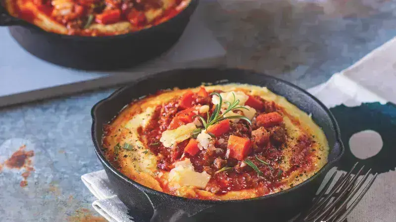 Polenta s masovou omáčkou v železném pánvi na talíři.