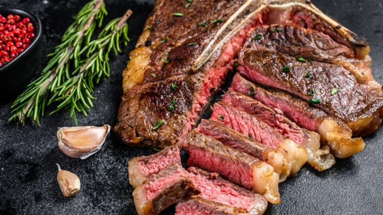 Odloupaný hovězí steak s růžovými vnitřky na tmavém podkladu.