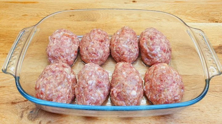 Surové mleté masové kuličky v skleněné formě na pečení.
