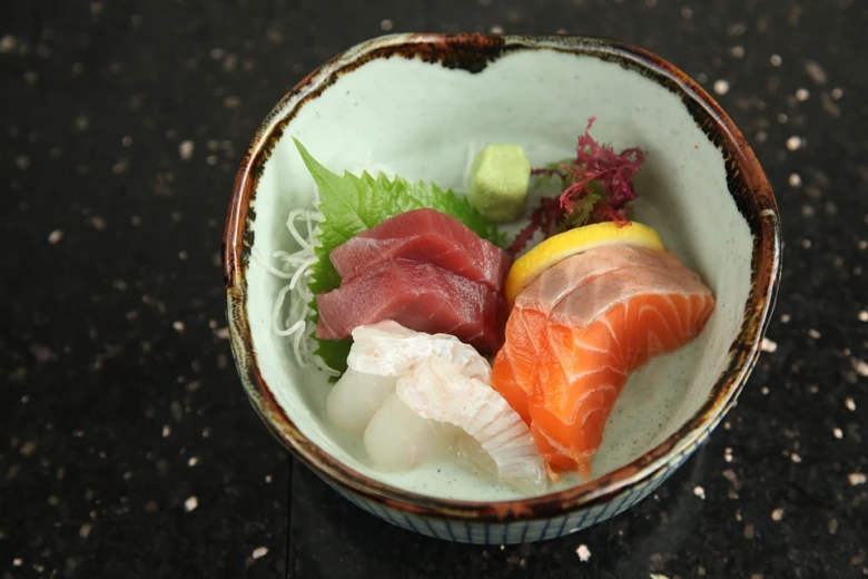 Mísa s různými druhy surového rybího sushi v keramické misce.
