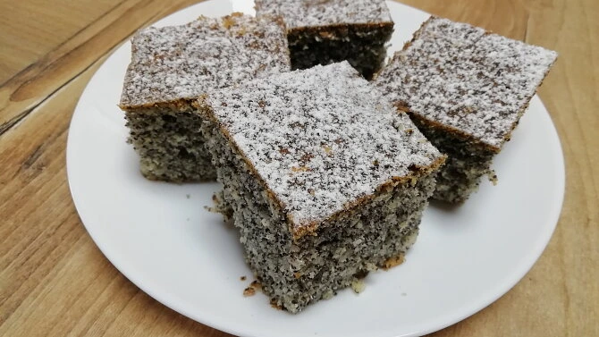 Kusy makového koláče posypané moučkovým cukrem na talíři.