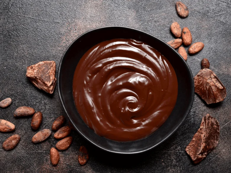 Čokoládová ganache v misce s kakaovými bobulemi.
