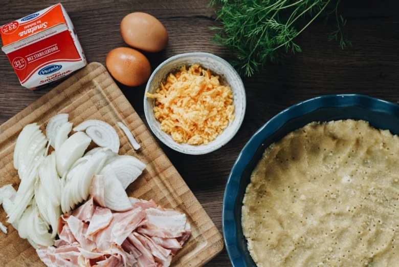 Ingredience pro solený koláč: cibule, šunka, vejce, sýr a těsto.