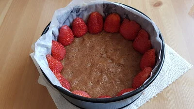 Nepečený cheesecake s jahodami: krusta obklopená čerstvými jahodami v pekáči.